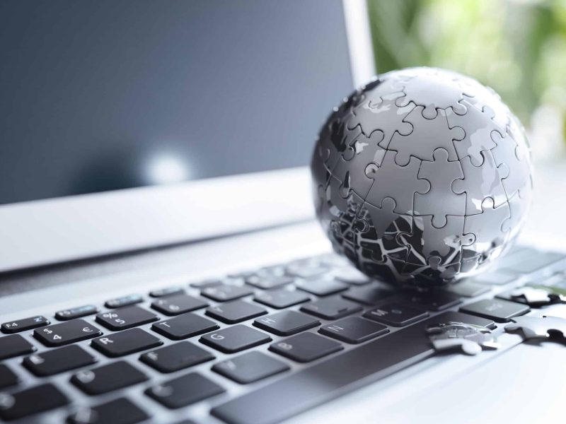 Global strategy solution concept - chrome earth jigsaw puzzle on laptop keyboard
